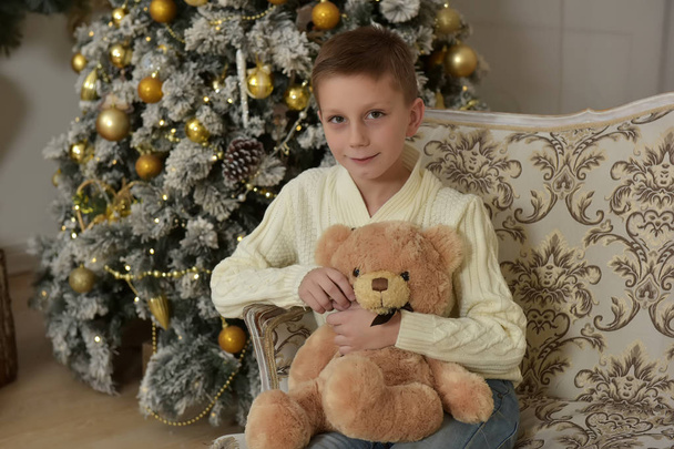 boy with a teddy bear at a Christmas tree at Christmas - Φωτογραφία, εικόνα