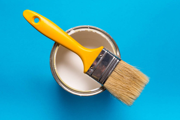 Brush and paint can on blue background - Φωτογραφία, εικόνα