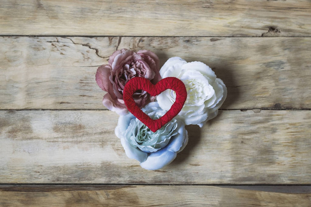 Valentinstag-Konzept. drei Rosen und ein handgefertigtes Herz auf einem Tuch - Foto, Bild