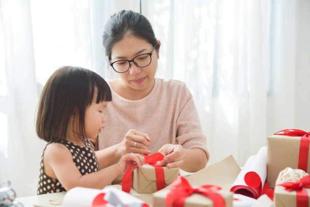 Young mother and her daughter wrapping a gift box. - Foto, immagini
