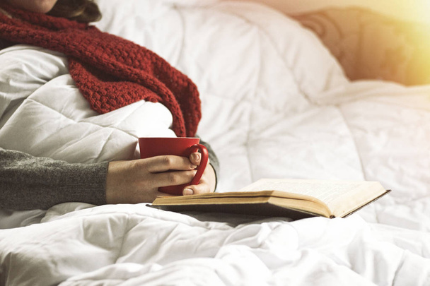 Menina na cama com um livro e uma xícara de chá quente. Efeito adicionado
 - Foto, Imagem