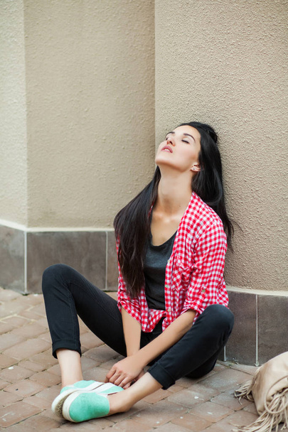teenager sitting on the ground leaning against the wall - Photo, image