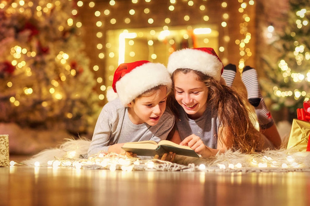 Two children on the floor read a book in a room  with Christmas - Foto, Imagem