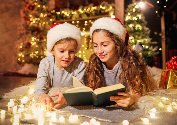Dwoje dzieci w pokoju zdobią dekoracje na Boże Narodzenie. - Zdjęcie, obraz
