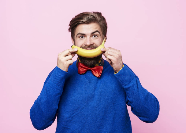 Hombre sosteniendo un plátano delante de su boca
  - Foto, imagen