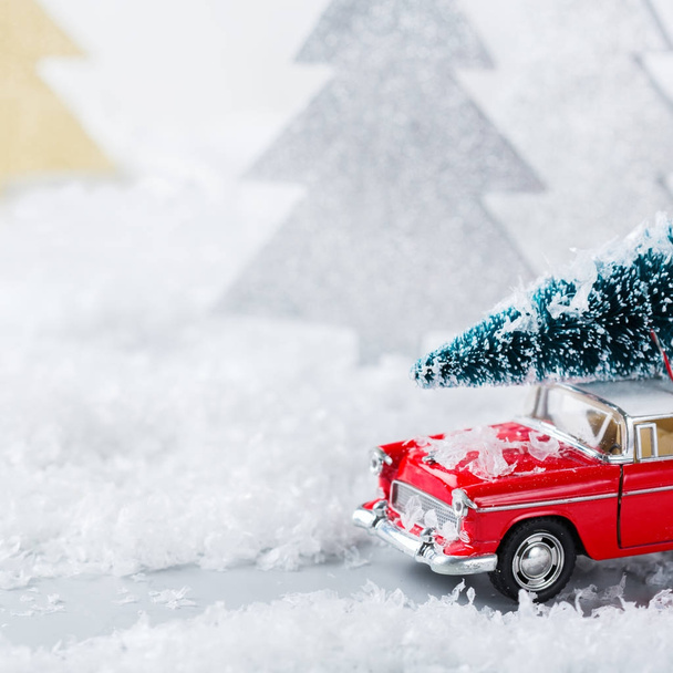 Toy car carrying christmas tree in a snow forest - Фото, зображення