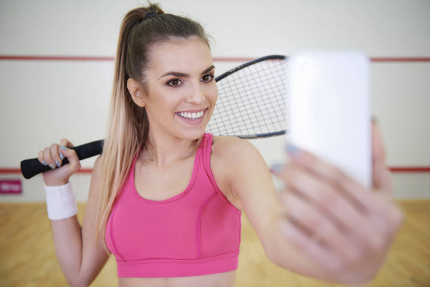 Young female player with mobile phone taking a selfie on court  - Fotoğraf, Görsel