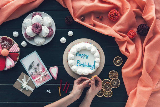 donna mettendo candela sulla torta di compleanno
 - Foto, immagini
