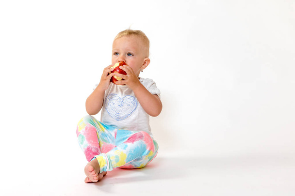 Whole view of toddler girl eating red apple - Φωτογραφία, εικόνα