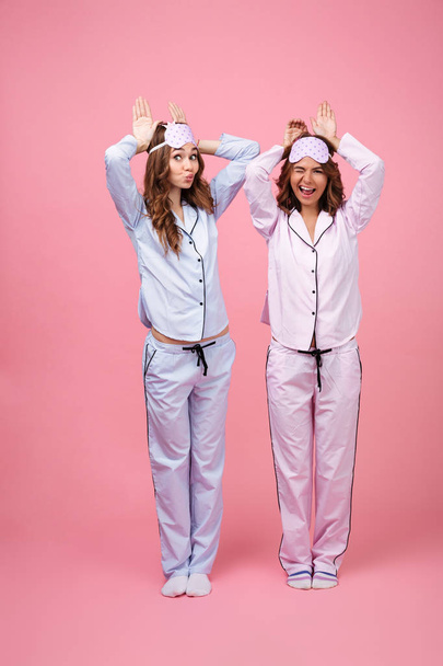 Funny two girls friends in pajamas isolated over pink background - Fotografie, Obrázek