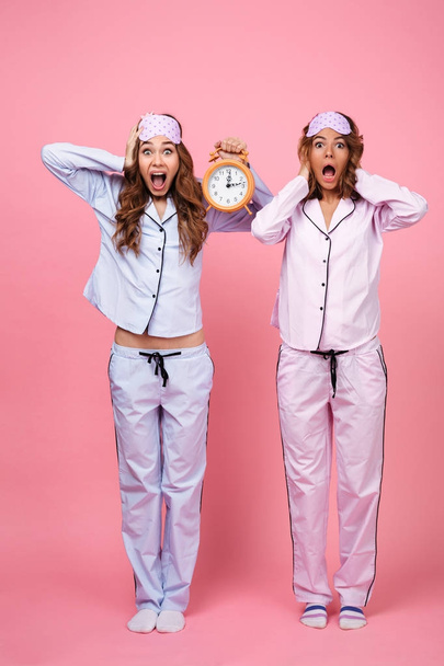 Two shocked confused screaming friends women holding alarm - Foto, Imagem