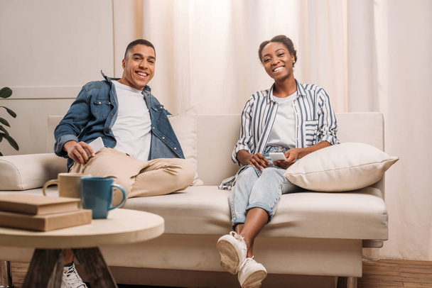 スマート フォンで座っているアフリカ系アメリカ人のカップル - 写真・画像