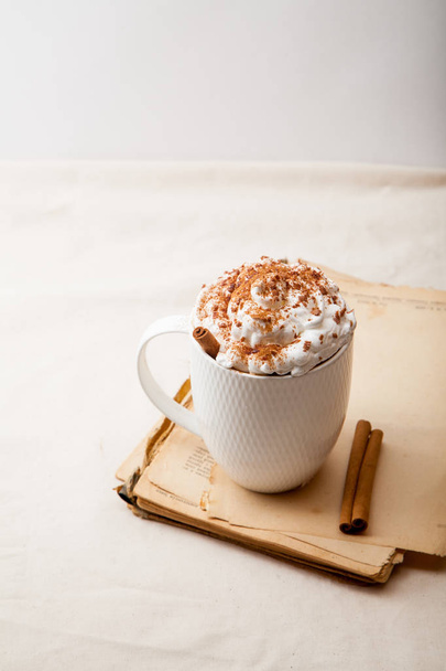 Cup of cocoa with cinnamon, whipped cream and chocolate. Textile background. Scandinavian winter concept. Vertical composition. - Фото, зображення