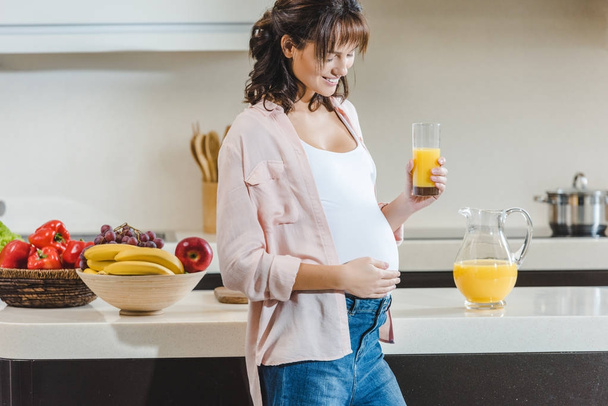 pregnant woman with juice touching belly - Zdjęcie, obraz