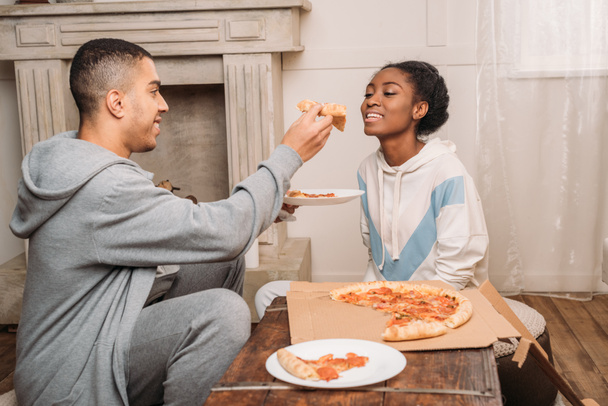 man sharring pizza slice to girlfriend - 写真・画像