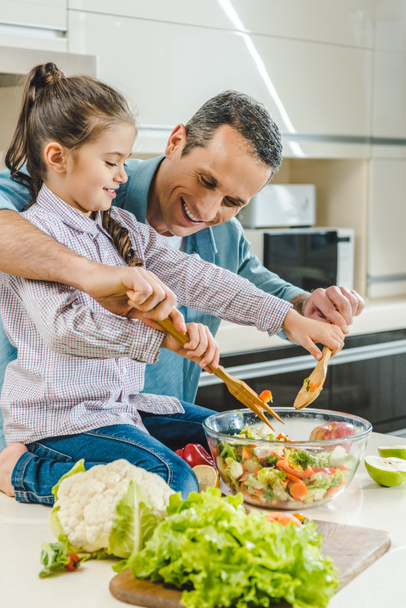 father with daughter mixing salad in bowl  - Photo, Image