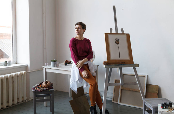 Female artist in her spacious white studio working with watercolor painting.  Natural lighting. Disclosure of creativity concept. Horizontal composition. - Fotoğraf, Görsel