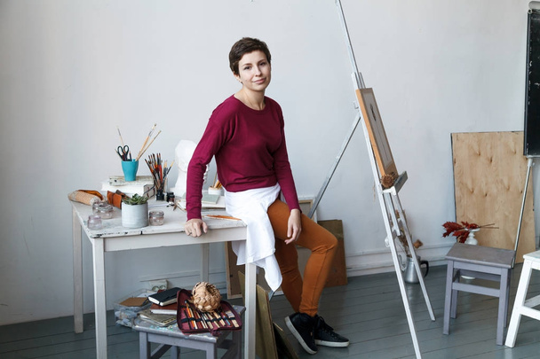 Female artist in her spacious white studio working with watercolor painting.  Natural lighting. Disclosure of creativity concept. Horizontal composition. - Photo, Image