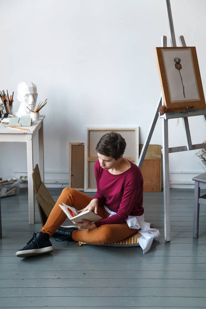 Female artist in her spacious white studio working with watercolor painting.  Natural lighting. Disclosure of creativity concept. Vertical composition with copy space - Foto, afbeelding