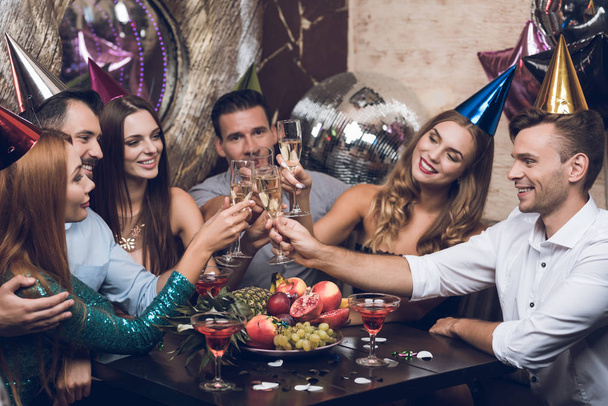 Молодые люди отдыхают в модном ночном клубе. Они звонят в бокалы и пьют шампанское
. - Фото, изображение