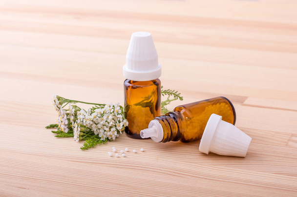 Homeopathisch middel / Homeopathische verhelpen met bloeiende duizendblad met een houten achtergrond  - Foto, afbeelding