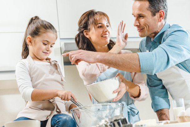 happy family making dough and looking at each other at kitchen - Foto, Imagem