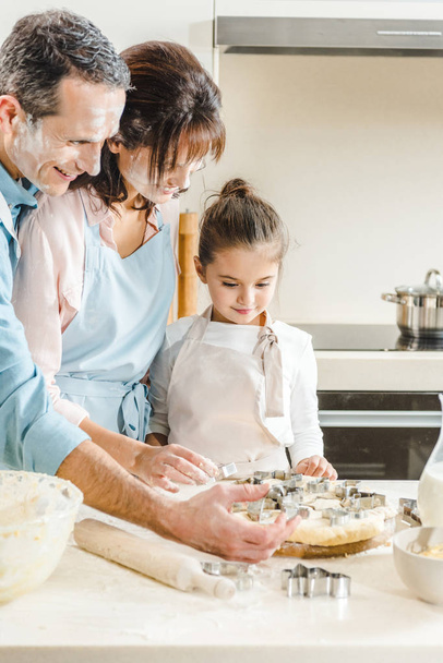 ευτυχισμένη οικογένεια Καυκάσιος στο αλεύρι κάνοντας φόρμες ζύμης στην κουζίνα - Φωτογραφία, εικόνα