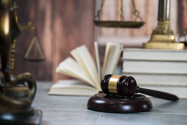 Концепция права - Открытая книга законов с деревянными судьями, молотком на столе в зале суда или в офисе правоохранительных органов на синем фоне. Копирование текста
 - Фото, изображение