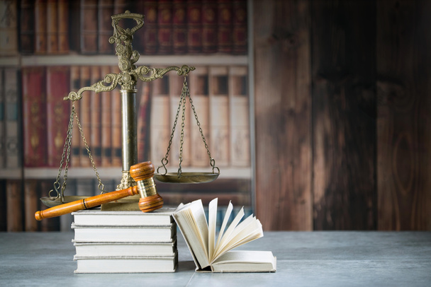 Концепция права - Открытая книга законов с деревянными судьями, молотком на столе в зале суда или в офисе правоохранительных органов на синем фоне. Копирование текста
 - Фото, изображение