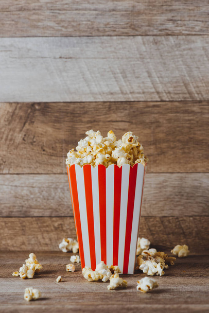 Popcorn en carton rouge et blanc sur table en bois
. - Photo, image