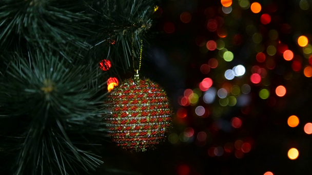 Kerstspeelgoed op een kerstboom tegen een bloemenslinger in de waas - Video