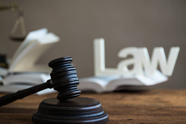 Gesetzeskonzept - offenes Gesetzbuch mit einem hölzernen Richtergabel auf dem Tisch in einem Gerichtssaal oder einer Strafverfolgungsbehörde auf blauem Hintergrund. Kopierraum für Text - Foto, Bild