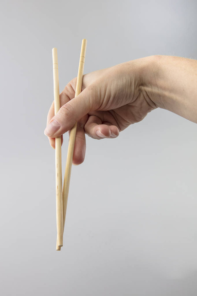 Dívka drží bambusové hůlky pro sushi - Fotografie, Obrázek