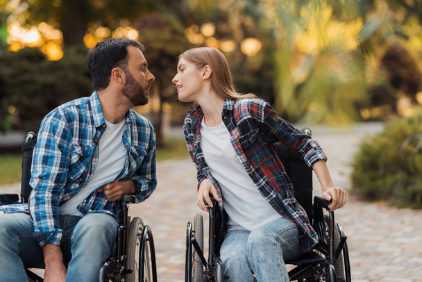 A couple of invalids on wheelchairs met in the park. They are drawn to each other for a kiss. - Foto, Bild