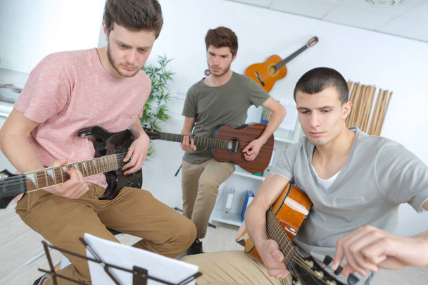 happy young men playing guitar with friends at home - Foto, afbeelding