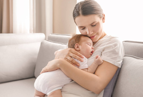 Young mother holding sleeping baby at home - Foto, Bild