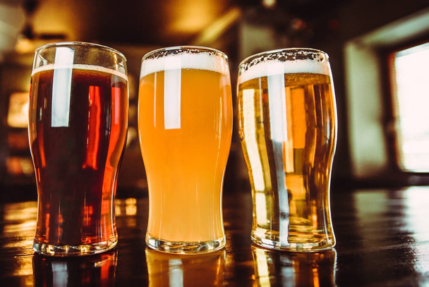 Vasos de cerveza clara y oscura sobre fondo de pub
 - Foto, Imagen