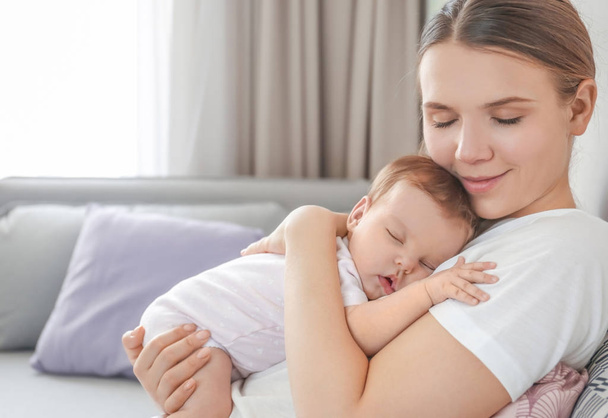 Young mother holding sleeping baby at home - Photo, Image