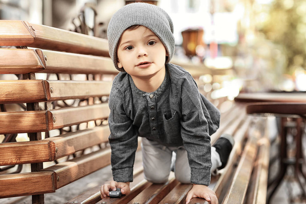 Adorable little boy on bench in outdoor cafe - Foto, Imagem