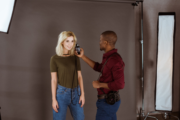 アフリカ系アメリカ人のカメラマンとスタジオで写真撮影を持つ白人モデル - 写真・画像