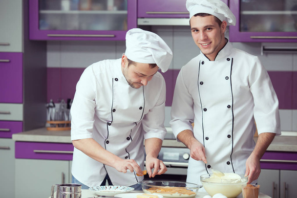 Tiramisu cooking concept. Portrait of two smiling men in cook uniform - Foto, Bild