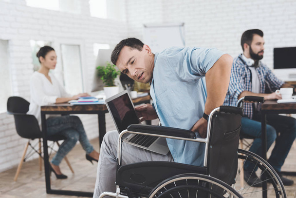 Disabled person in the wheelchair works in the office. He feel desease. - 写真・画像