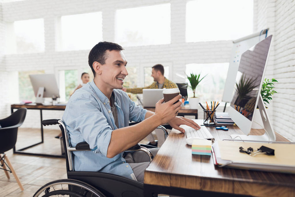 Disabled person in the wheelchair works in the office at the computer. - Фото, зображення