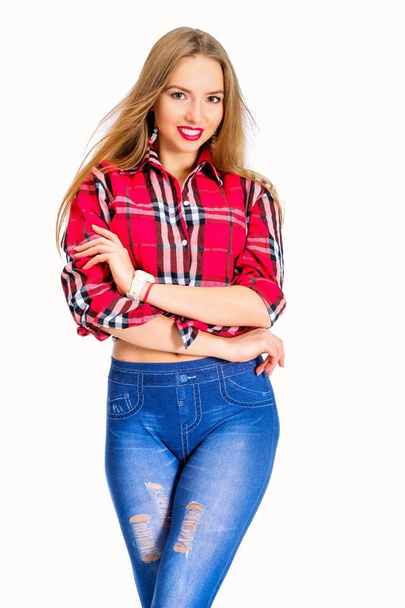 Young sexy woman dressed in jeans and checkered shirt posing in studio - Foto, Imagen