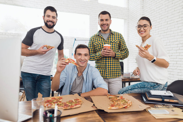 Office workers and man in a wheelchair are eating pizza. They work in a bright and modern office. - Photo, image