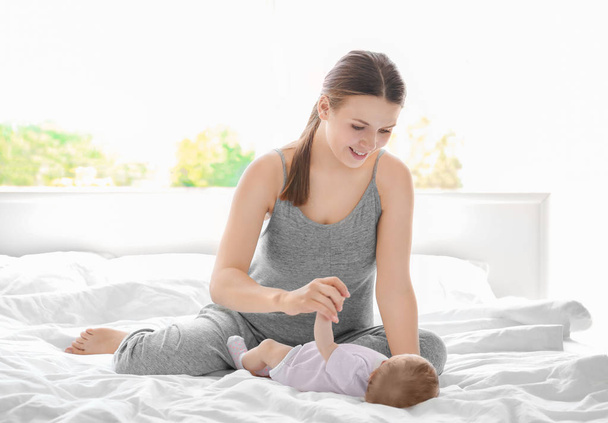 Young mother with baby on bed at home - Foto, Imagen
