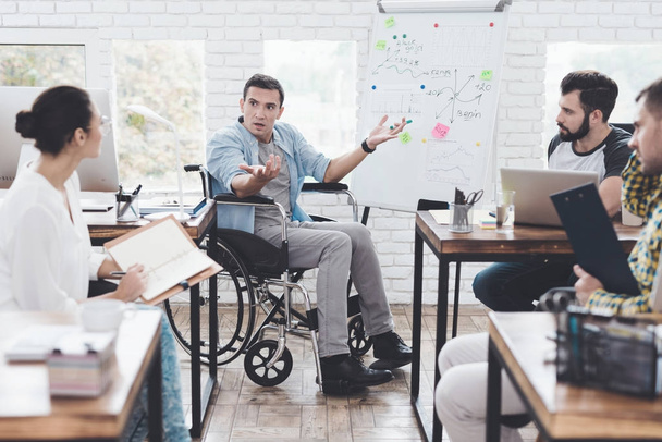Toimistotyöntekijät ja pyörätuolissa istuva mies keskustelevat bisneshetkistä modernissa toimistossa
. - Valokuva, kuva