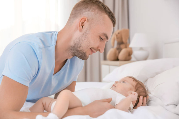 Young father with baby on bed at home - Fotoğraf, Görsel