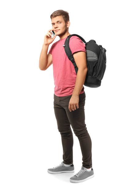 Teini-ikäinen poika puhuu matkapuhelimella valkoista taustaa vasten
 - Valokuva, kuva