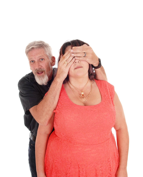 Homem segura as mãos sobre os olhos da esposa
 - Foto, Imagem